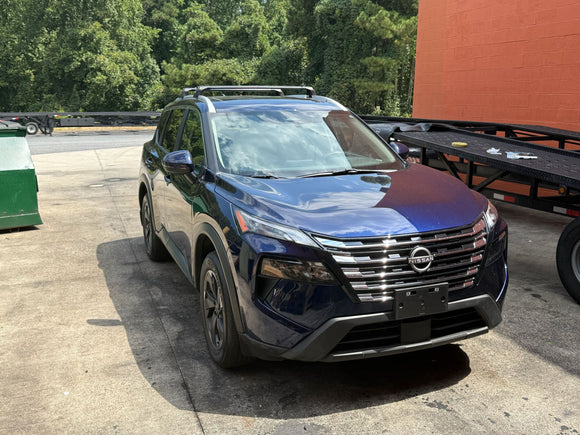 Blue SUV parked on a paved surface with trees in the background