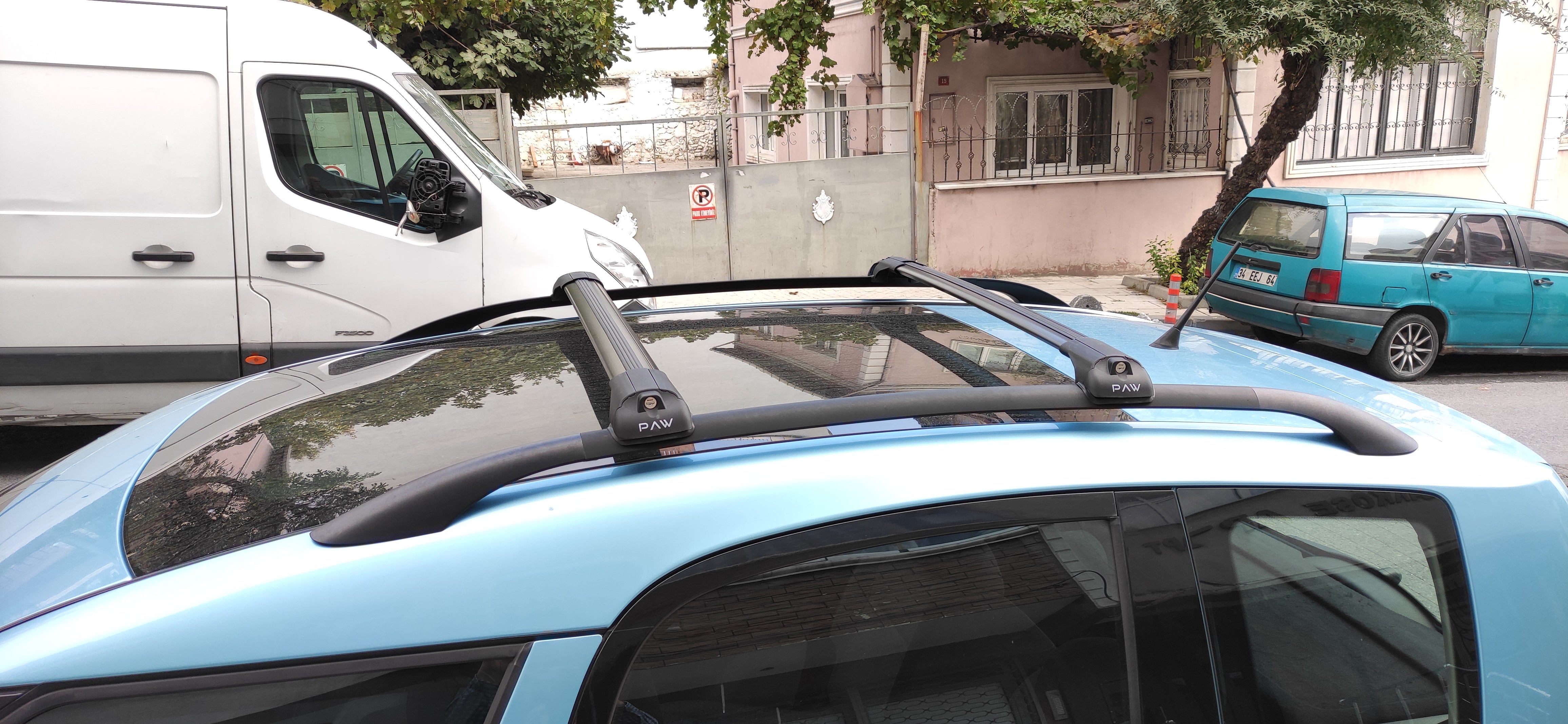 Car with roof rack on a street with buildings and trees in the background