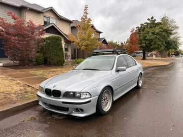 Silver BMW car with roof racks parked on a residential street