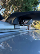 Close-up of a car roof rack system with trees in the background