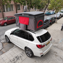 Roof rack cross bars supporting rooftop tent and camping gear