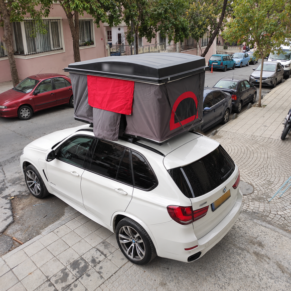 Roof rack cross bars supporting rooftop tent and camping gear
